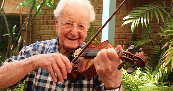Kincare customer Cliff playing the violin and smiling