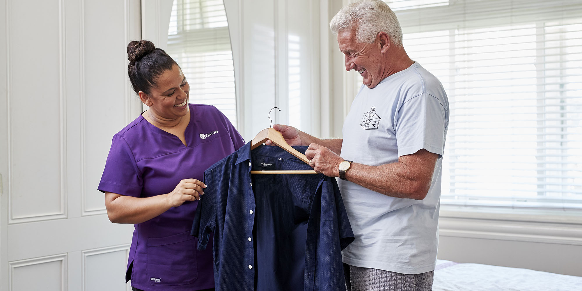 A KinCare home care worker assists her customer to get dressed