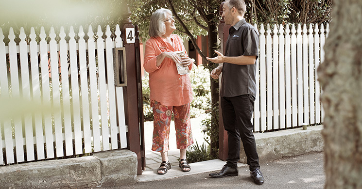 elderly woman and kincare worker standing outside her house