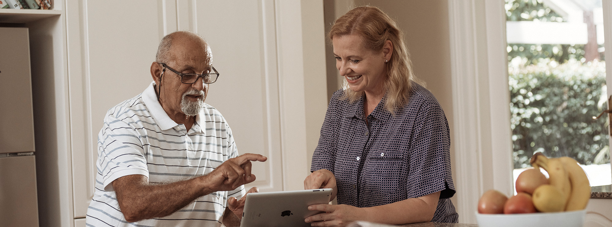 kincare worker teaching elderly man how to use ipad