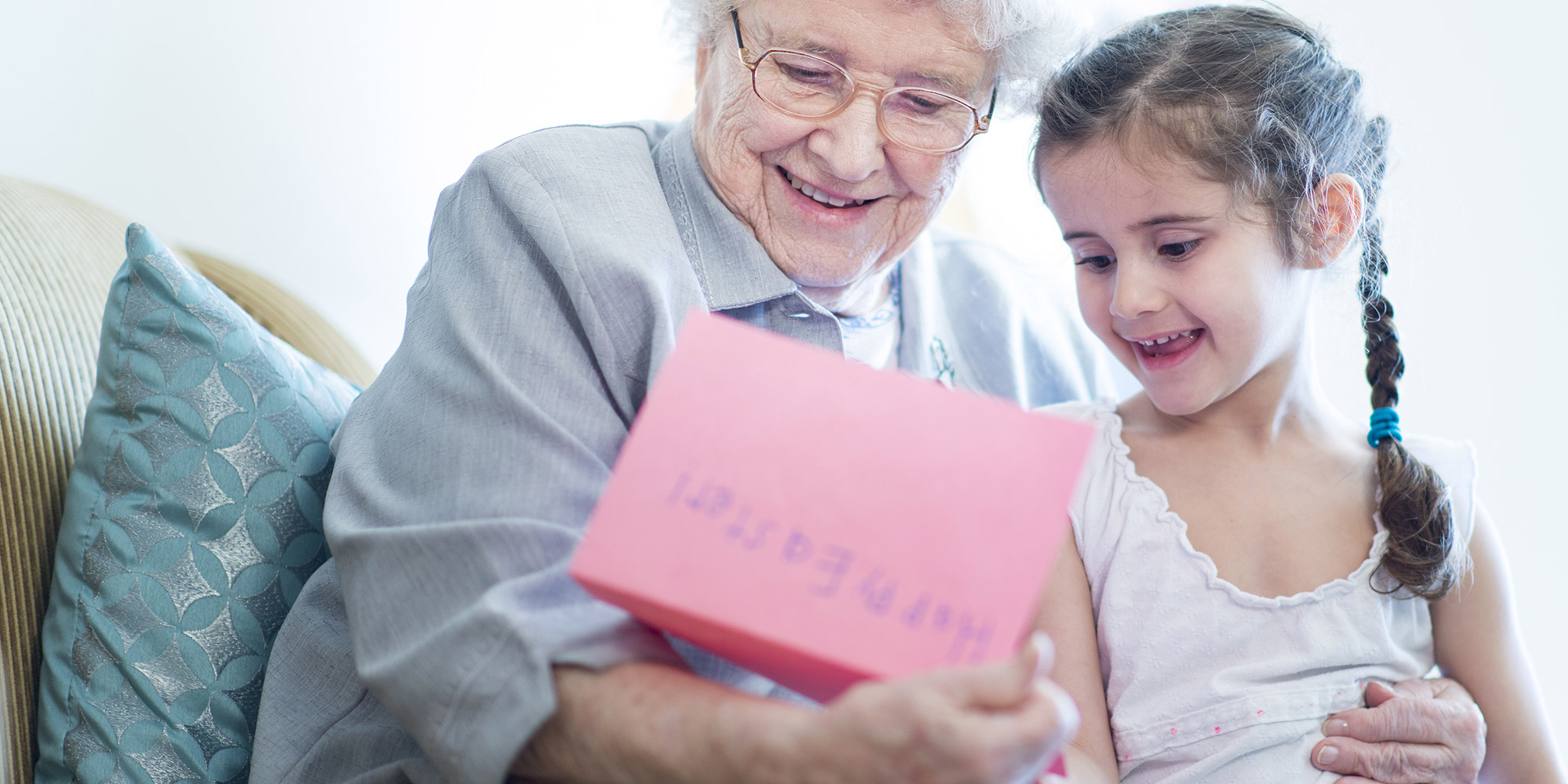 elderly woman holding a happy easter card next to her granddaughter smiling