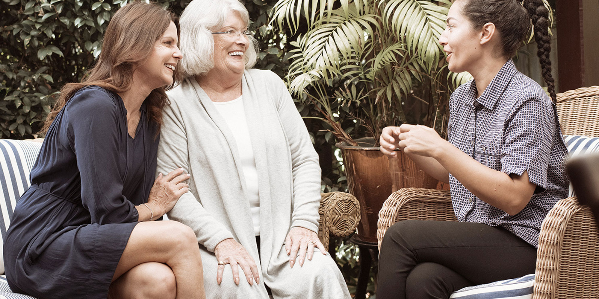 Elderly woman and family member sitting opposite kincare worker chatting