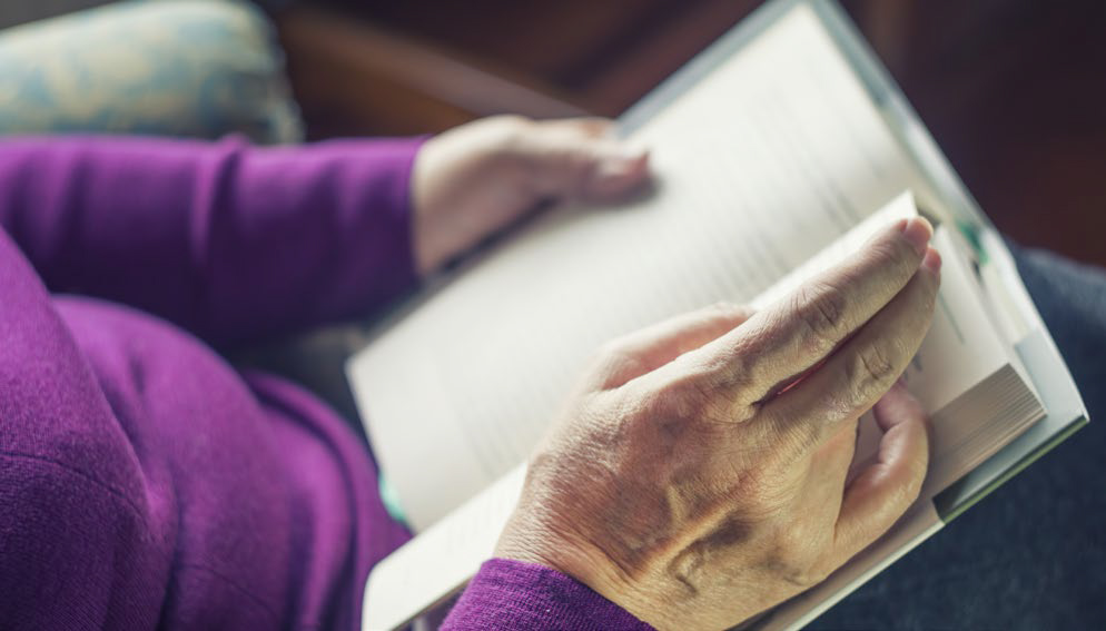 elderly woman reading a book in her lap