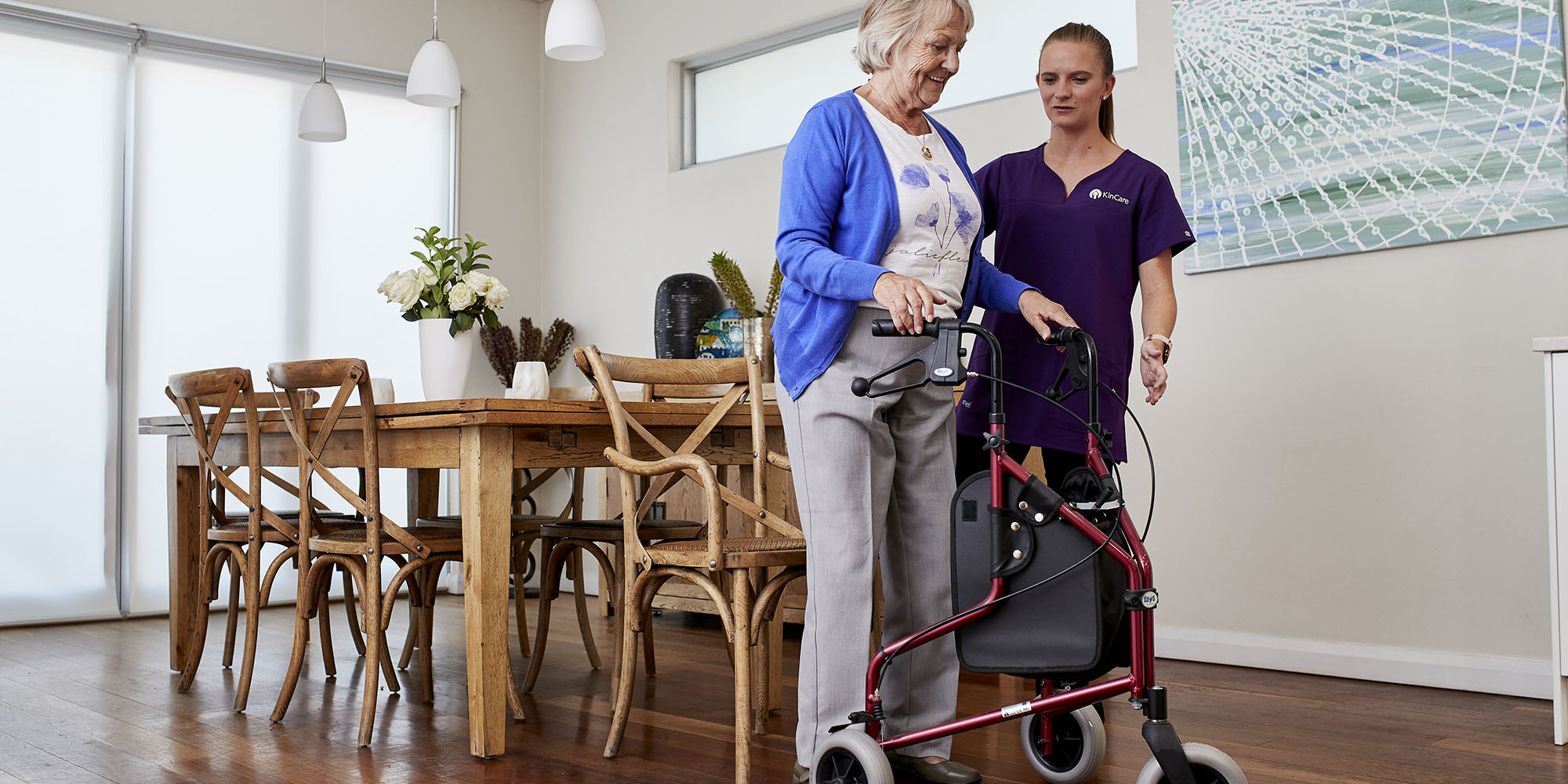A woman is assisted to use her walker by a KinCare Home Care Worker