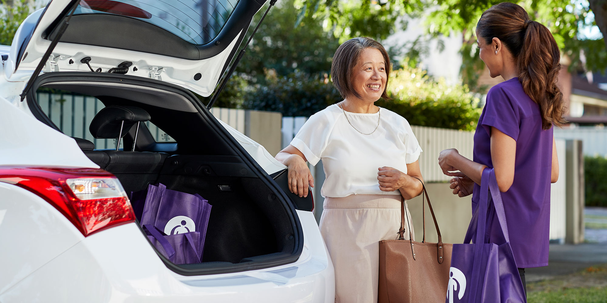 Kincare worker helping elderly customer rearrange her car boot