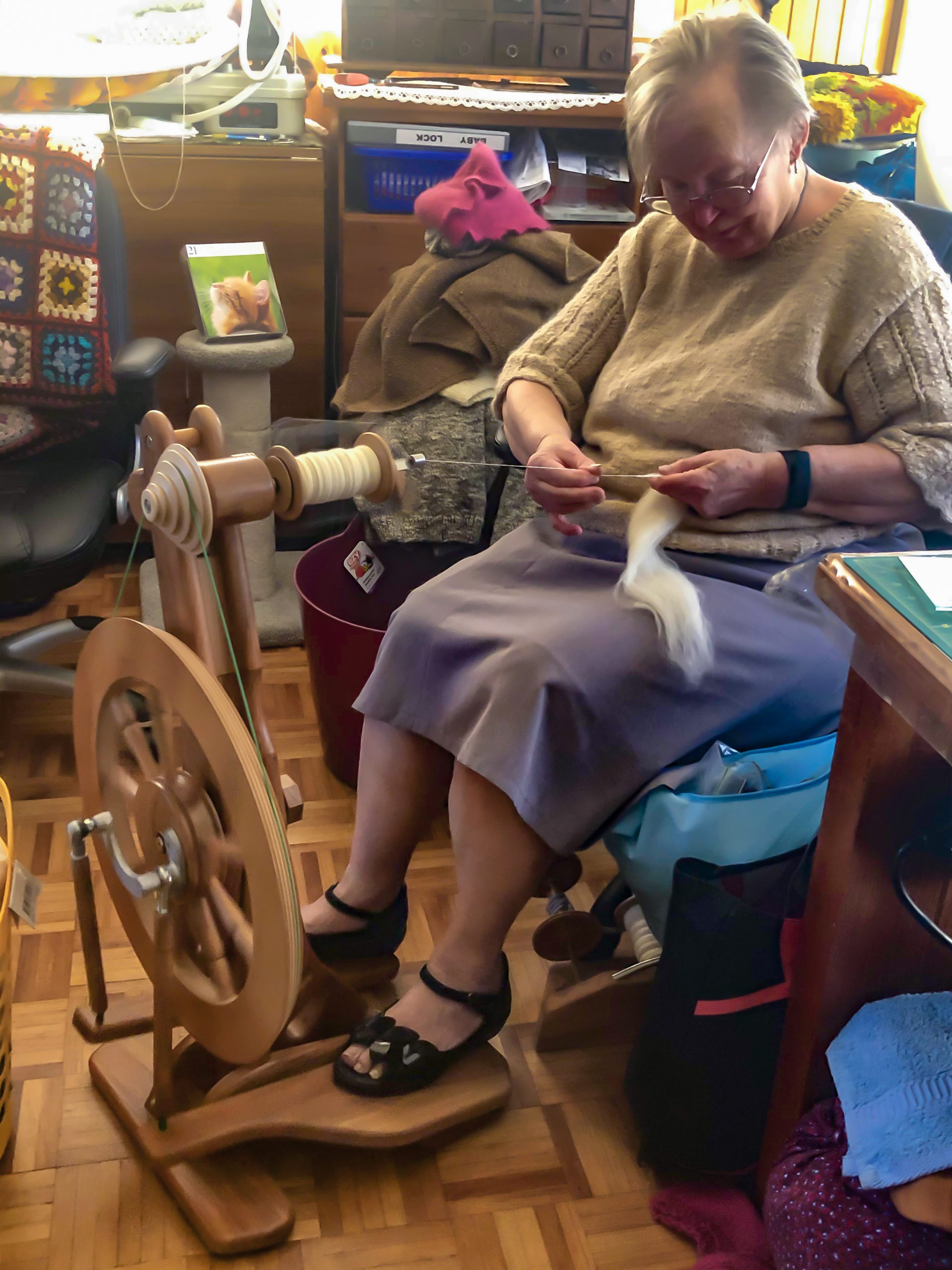 KinCare Customer Nelly sitting and threading fibres through a spinning thread machine