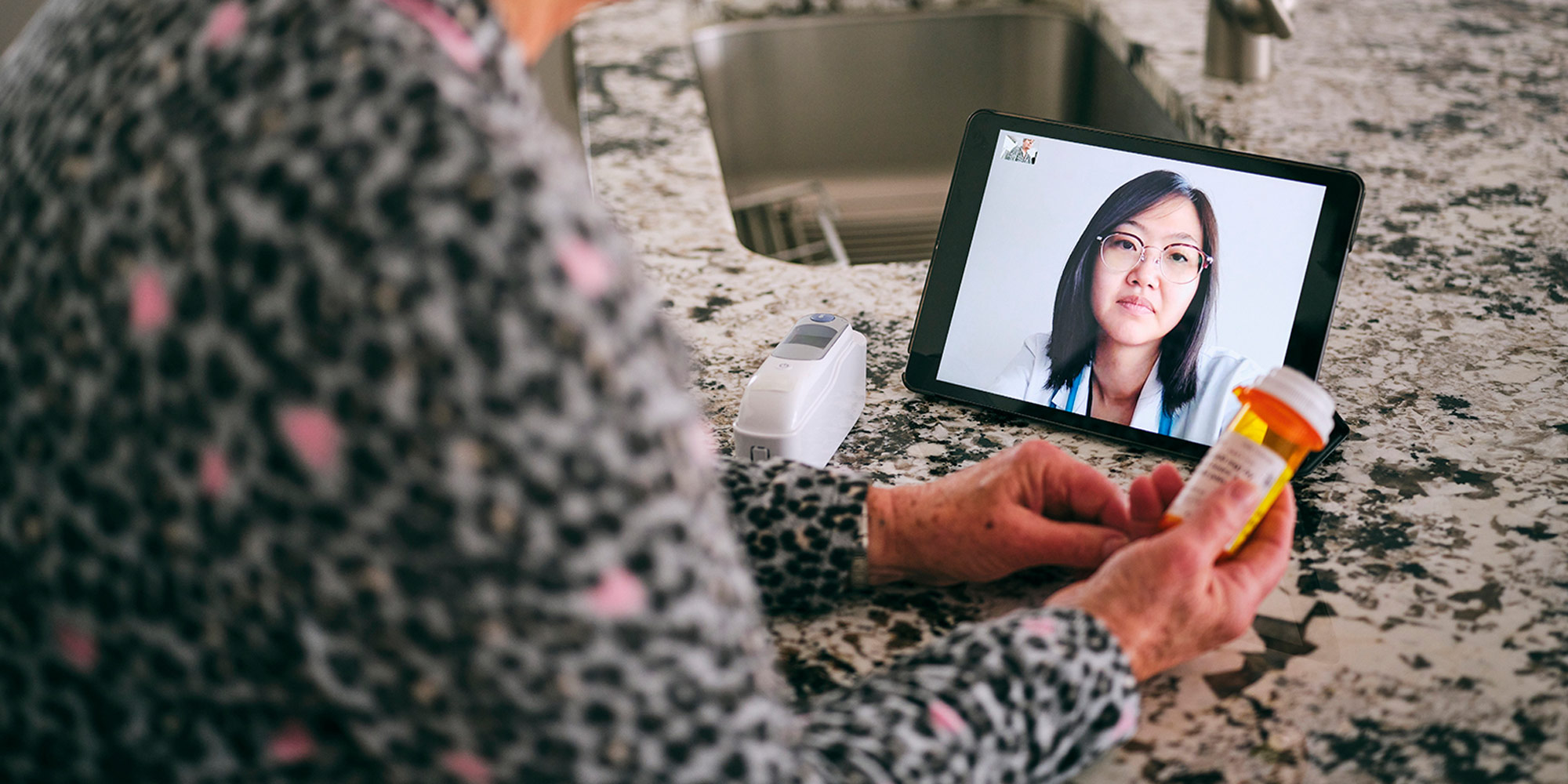 elderly woman video calling her doctor on an ipad holding on to her medication