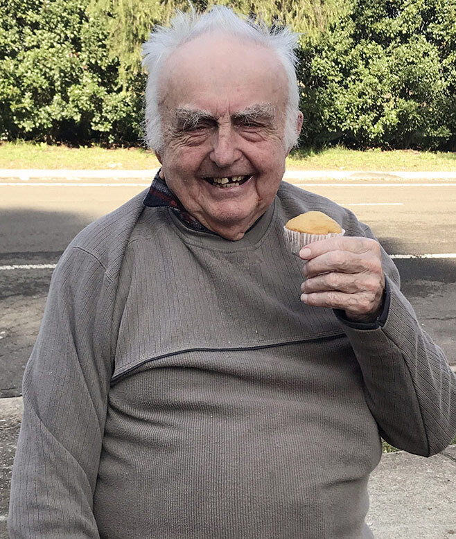 Kincare Customer Robert smiling and holding up the muffin he learnt to bake