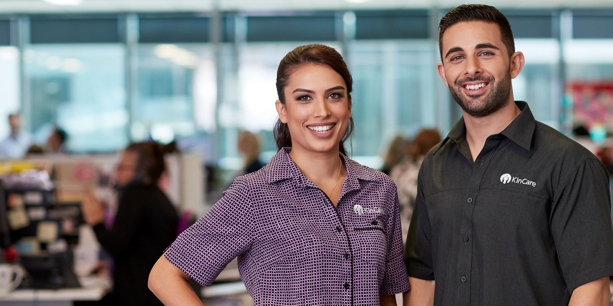 A female and a male home care worker smiling at the office