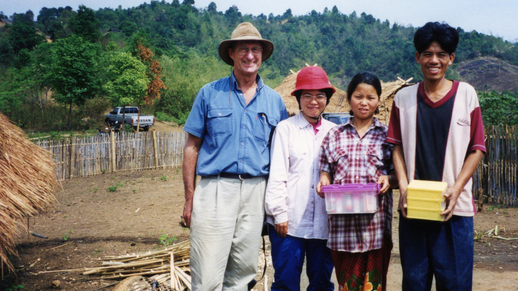 Customer Dr Anthony Radford smiling with three health care workers in rural Northern Thailand Akha village