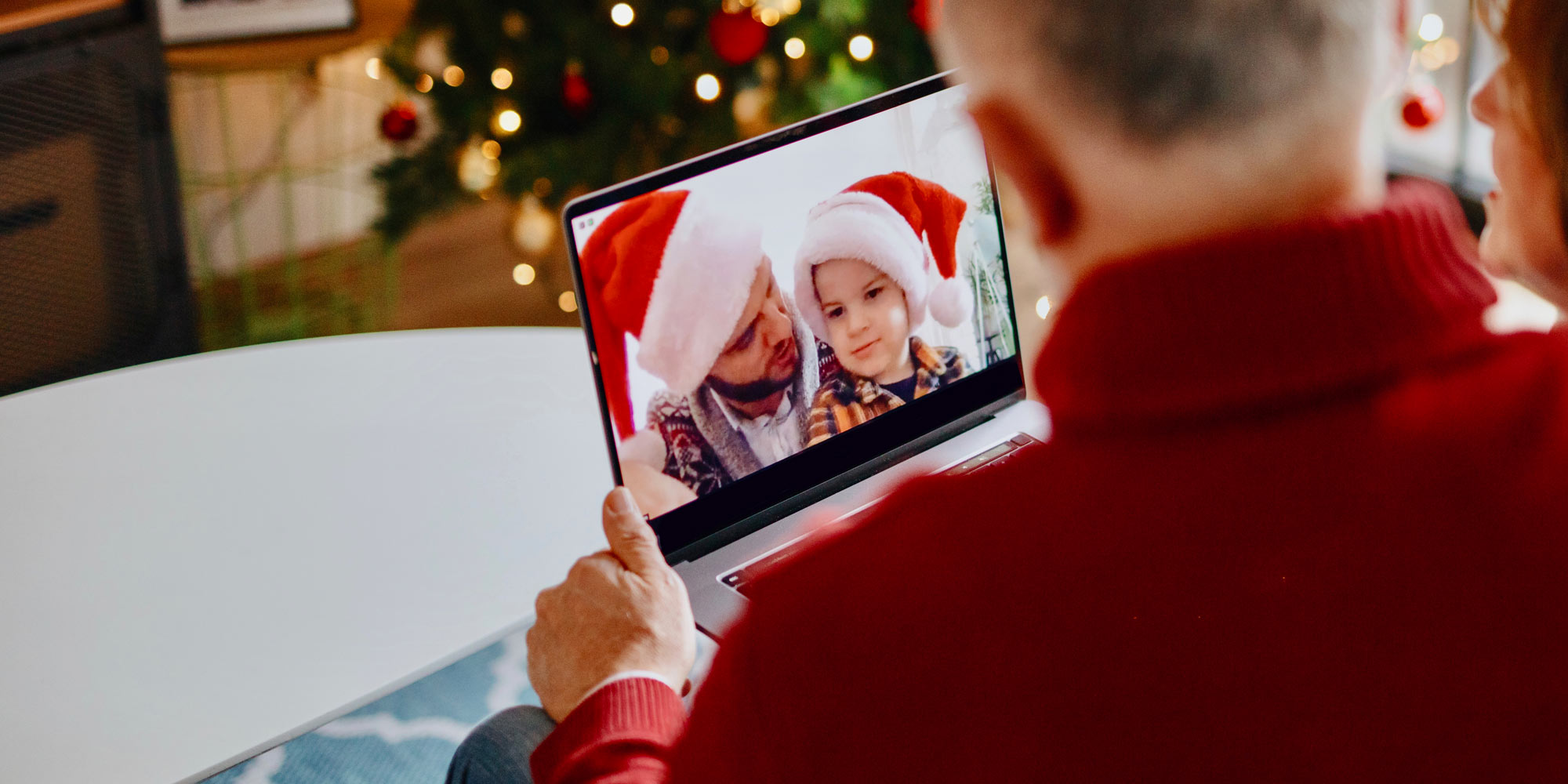 Elderly couple using the computer to video call grandson and son wearing santa hats