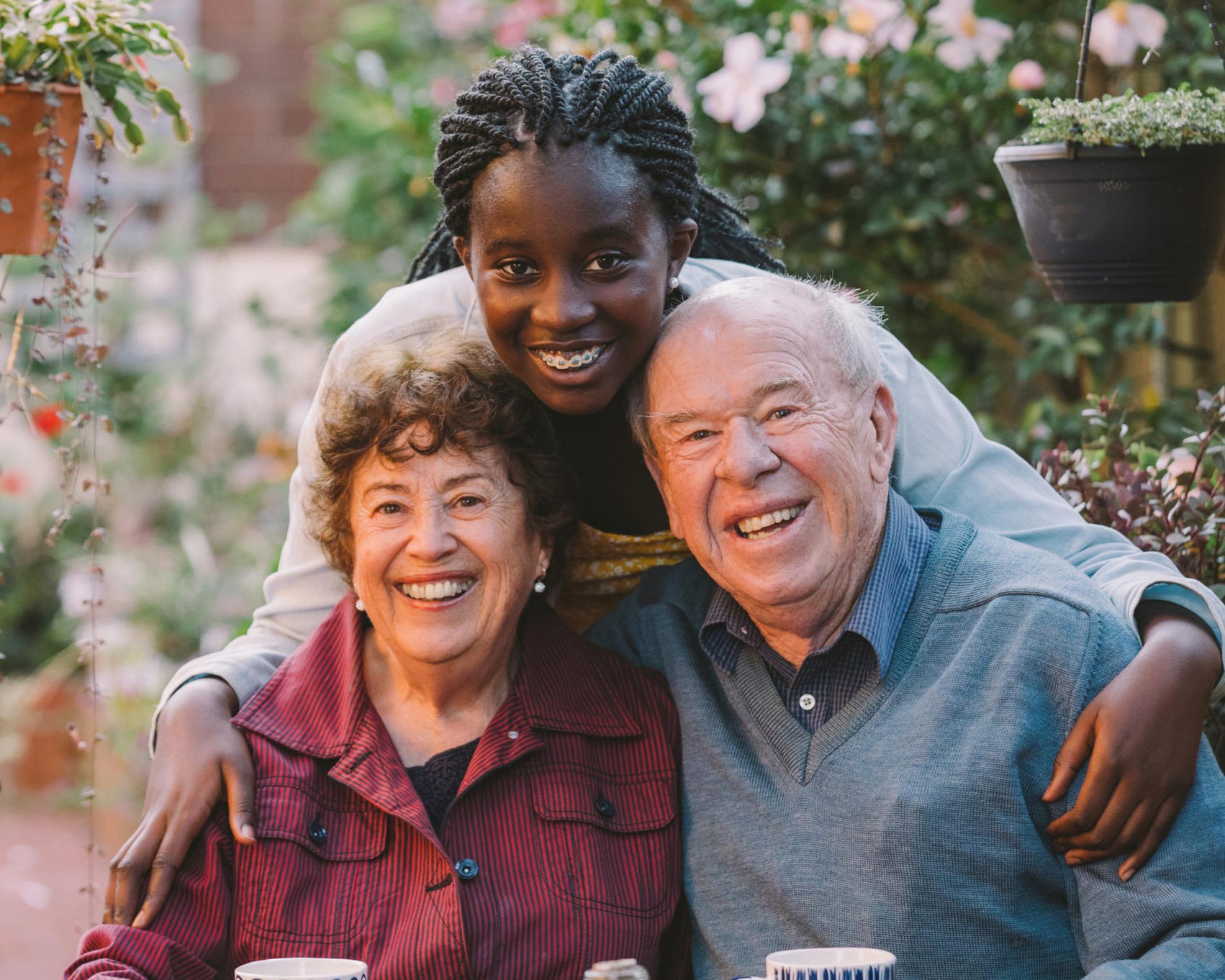 Honorary granddaughter Keenor hugging and smiling with elderly kincare couple Merle and Rick