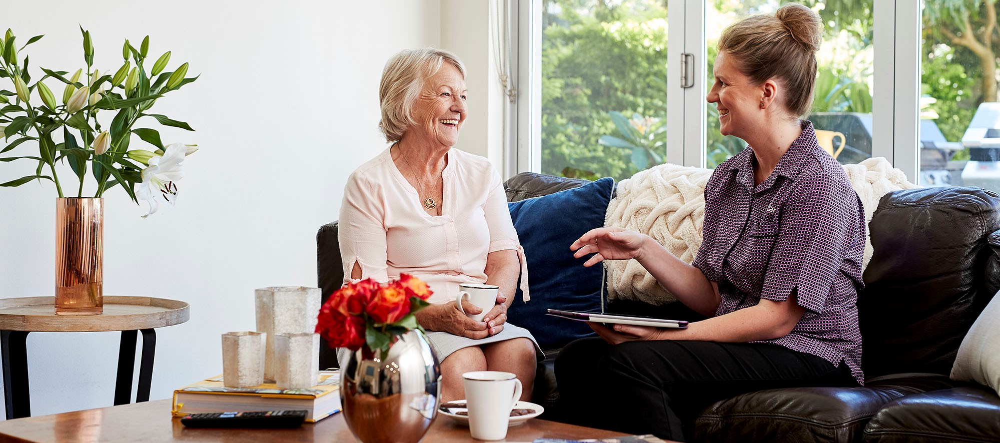 Kincare worker and customer sitting and talking happily around the coffee table