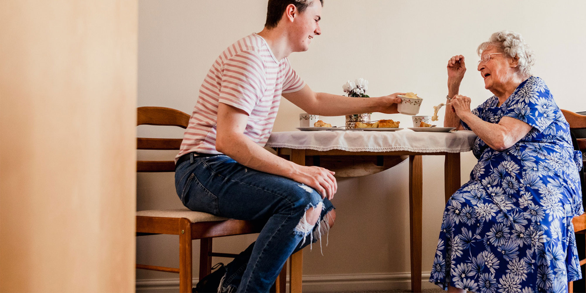 Kincare carer and elderly customer with dementia smiling around the dinner table at home